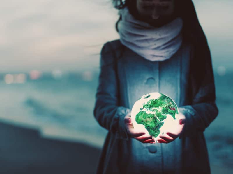 marketing trends - earth globe glowing in woman hands on beach